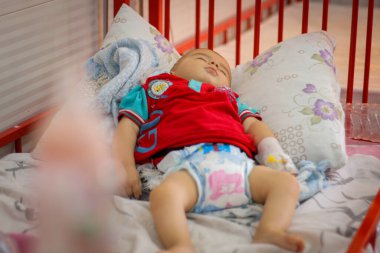 Halep, Suriye 01 Mart 2020: Bir anne hasta çocuğunun yatağında uzanan elini tutuyor. Sevimli yeni doğmuş bebek kuvöz bakım hastanesinde uyuyor..