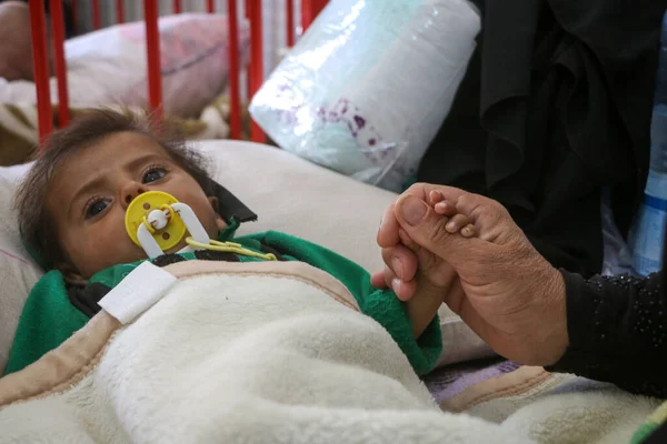 Halep, Suriye 01 Mart 2020: Bir anne hasta çocuğunun yatağında uzanan elini tutuyor. Sevimli yeni doğmuş bebek kuvöz bakım hastanesinde uyuyor..