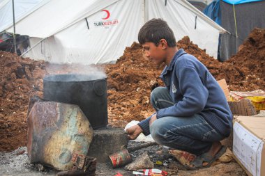 Halep, Suriye, 20 Aralık 2019Kamptaki bir mülteci çocuk açık havada odun pişiriyor..