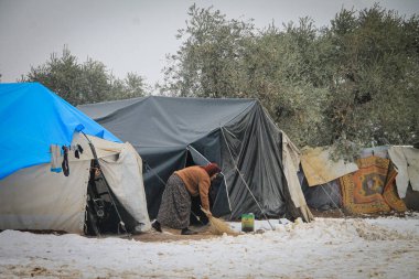 Halep, Suriye, 15 Şubat 2017. Bir kadın karların içinde yaşadığı çadırı temizliyor.
