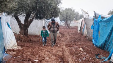 Halep, Suriye 15 Şubat 2017 Bir mülteci kadın kamptaki kar sırasında kafasında bir kova su tutuyor.