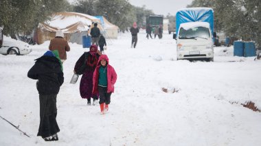 Halep, Suriye 15 Şubat 2017 Bir mülteci kadın kamptaki kar sırasında kafasında bir kova su tutuyor.