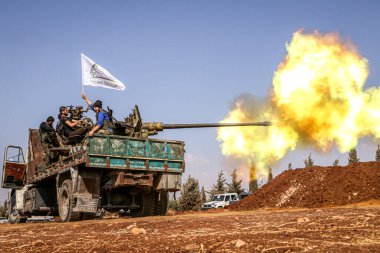 Halep, Suriye 14 Mart 2016: Suriyeli silahlı muhalif askerler IŞİD savaşçılarına ağır silahlarla ateş açtılar. Parklar ve yangın dumanı