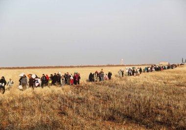 Halep, Suriye 11 Mart 2017: Bombalamadan kaçmak için tarlalar arasında büyük sivil gruplar yürüyor