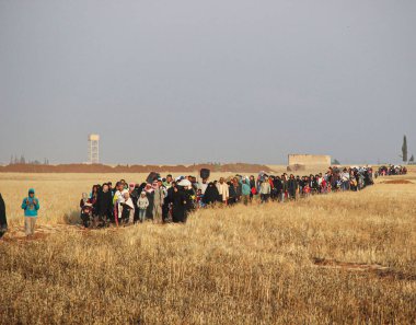 Halep, Suriye 11 Mart 2017: Bombalamadan kaçmak için tarlalar arasında büyük sivil gruplar yürüyor