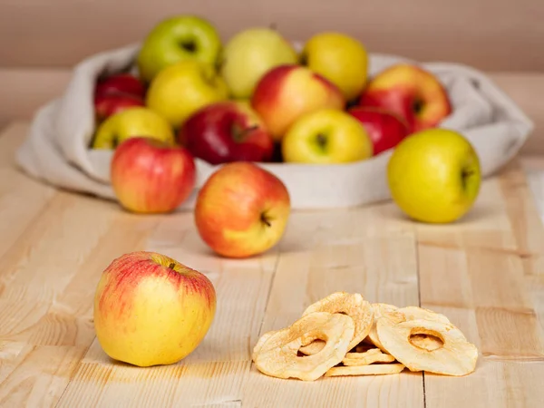 Red apple and dried apple slices on the background of sack of apples on the wooden planks