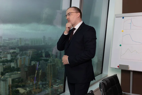 Mavi takım elbiseli, düşünceli, hüzünlü ama sakin bir yönetici şehrin üzerindeki gök gürültüsüne bakıyor ve kriz sorunlarını düşünüyor, kapat.