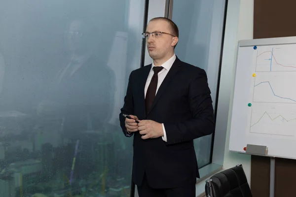 Resmi takım elbiseli bir işadamı, ofisteki anti-kriz toplantısından sonra pencerenin önünde durur. Kalemi tutar ve bir şeyler düşünür, kapatır.