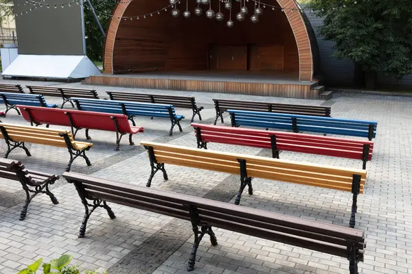 Parktaki açık hava tiyatrosu sahnesinden önce renkli banklar kapanıyor.