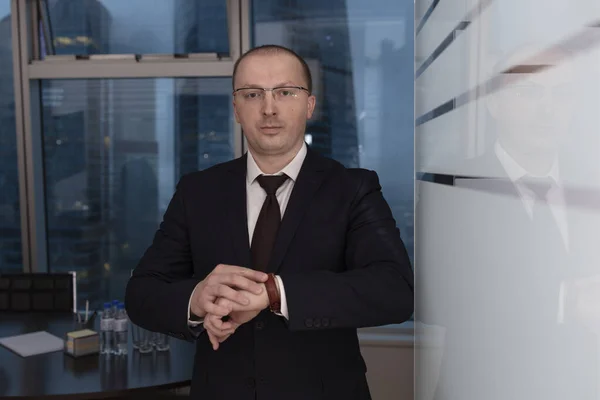 Kapıda katı bir yönetici toplantının gecikmiş katılımcılarını bekliyor ve saati nöbete göre kontrol ediyor, kapat 