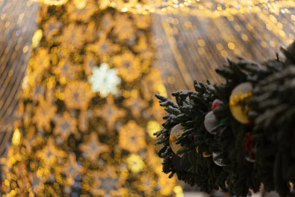 Yeni yıl çam dalları renkli toplar ve altın çelenklerle süslenmiş güzel Noel ağacı ve akşam parkında süslenmiş süsler.