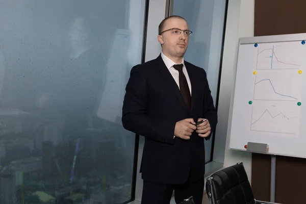 Mavi takım elbiseli ve beyaz gömlekli bir iş adamı ofisin penceresinden dönüp elinde kalemle karanlık yağmurlu bir akşamda kafasını kaldırıp, kapanıyor.