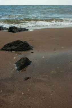 Okyanusta ıslak kum. İnsansız bir sahil. Dikey fotoğraf.