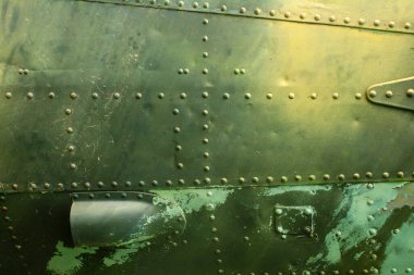 Eski bir uçak gövdesinin metal yüzeyinde haki renkli perçinler var..
