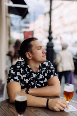 Mutlu ve çekici bir adam dinleniyor ve barda bira içiyor..