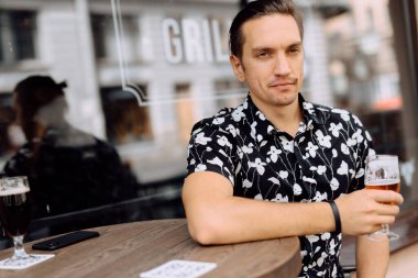 Mutlu ve çekici bir adam dinleniyor ve barda bira içiyor..