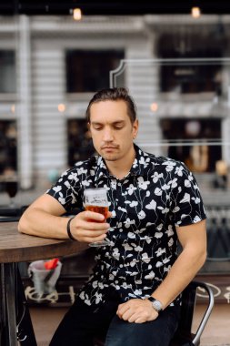 Mutlu ve çekici bir adam dinleniyor ve barda bira içiyor..