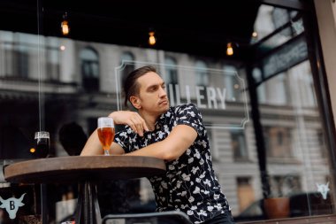 Mutlu ve çekici bir adam dinleniyor ve barda bira içiyor..