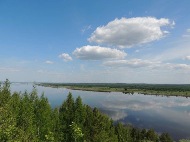 Ufukta ağaçlar ve önde ağaçlar olan güzel nehir manzarası.