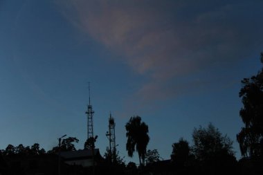 Karanlık ağaçlarla, gölgelerle ve demir binalarla güzel bir gün batımı.