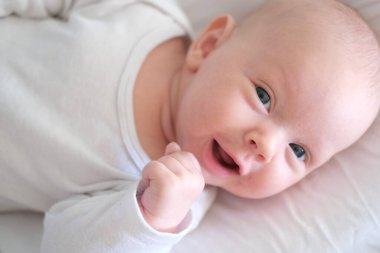  Beyaz elbiseli yeni doğmuş bir bebek yatakta yatıyor. Yalan söyleyen şirin bir çocuğun portresi.