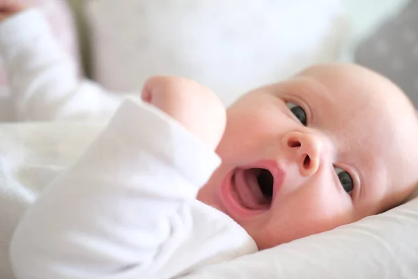 Bayi yang baru lahir dengan pakaian putih berbaring di tempat tidur. Potret seorang anak kecil yang lucu berbohong — Stok Foto