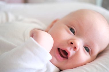  Beyaz elbiseli yeni doğmuş bir bebek yatakta yatıyor. Yalan söyleyen şirin bir çocuğun portresi.