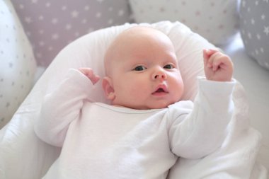  Beyaz elbiseli yeni doğmuş bir bebek yatakta yatıyor. Yalan söyleyen şirin bir çocuğun portresi.