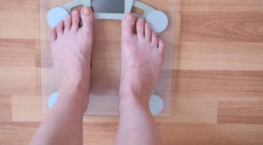 Kadın bacakları yakın. Vücut ağırlığını ölçmek için ölçek. Fazla kilolu konsept.