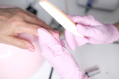 Profesyonel manikür, güzellik salonunda manikür. Eldivenler konusunda ustanın elleri. Tırnaklar parlatılıyor