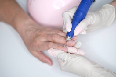 Tırnak bakımı. Usta manikür sırasında ojeli elleri kesmek için elektrikli makine kullanıyor..