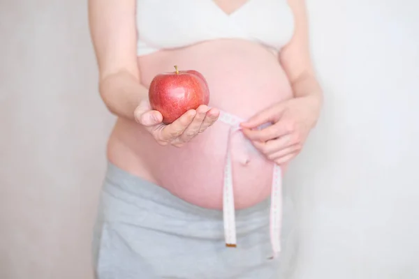 En gravid kvinna håller ett rött äpple i handen. Begreppet riktig kost — Stockfoto