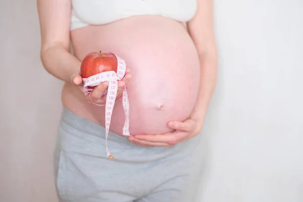 Uma mulher grávida tem uma maçã vermelha na mão. O conceito de nutrição adequada — Fotografia de Stock