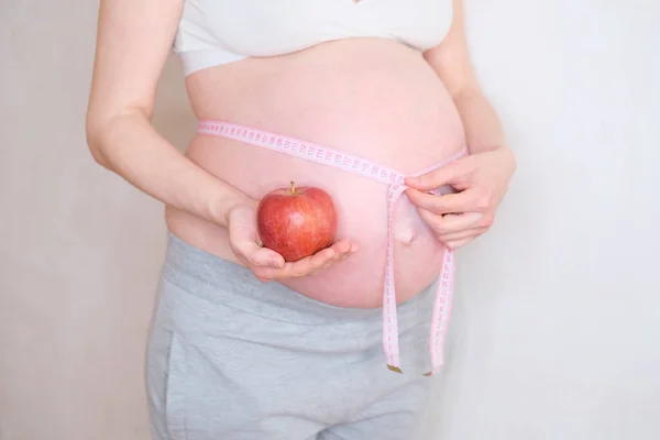 一个孕妇手里拿着一个红苹果。适当营养的概念 — 图库照片