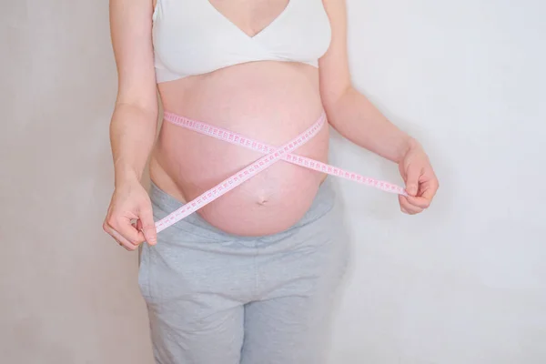 Těhotná žena si měří břicho. Koncept nadváhy. — Stock fotografie