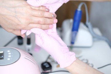 Tırnak bakımı. Usta manikür sırasında ojeli elleri kesmek için elektrikli makine kullanıyor..