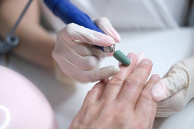 Tırnak bakımı. Usta manikür sırasında ojeli elleri kesmek için elektrikli makine kullanıyor..