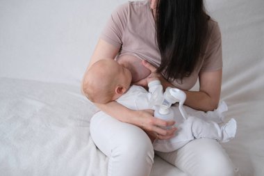 Bir kadın yeni doğan oğlunu emziriyor. Annem şişelere otomatik göğüs pompasıyla süt pompalar.