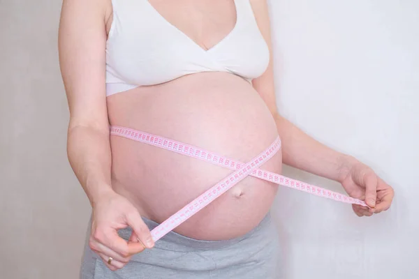 Eine schwangere Frau misst ihren Bauch. Übergewichtskonzept. — Stockfoto