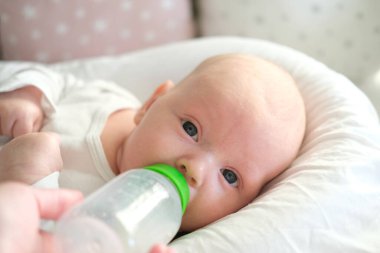 Bir çocuğun yakın plan portresi. Yeni doğmuş bir bebek şişeden süt içer.