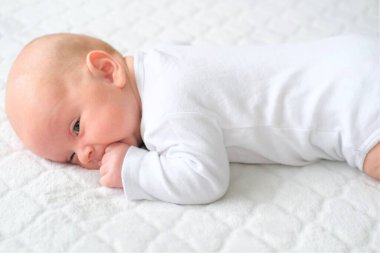 Yeni doğmuş bir bebek beyaz bir battaniyenin üzerinde yatıyor. Bir çocuğun yakın plan portresi