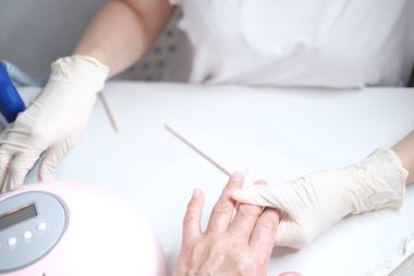 Profesyonel manikür, güzellik salonunda manikür. Eldivenler konusunda ustanın elleri. Tırnaklar parlatılıyor.