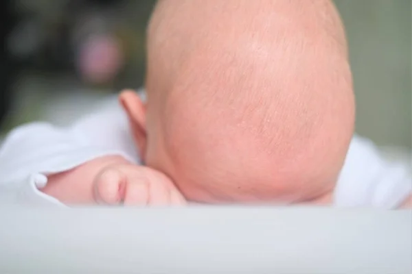 Un neonato giace su una coperta bianca. Childs testa da vicino. — Foto Stock