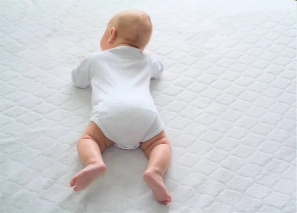 新生児は白い毛布の上に寝そべっている。子供は這うことを学ぶ. — ストック写真
