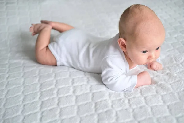 Egy újszülött egy fehér takarón fekszik. Egy gyermek közeli portréja — Stock Fotó