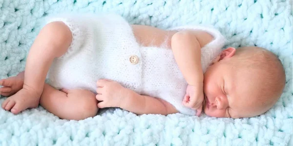 Un niño o niña recién nacido dormido yace sobre una manta de lana azul.Retrato de cerca de un niño — Foto de Stock