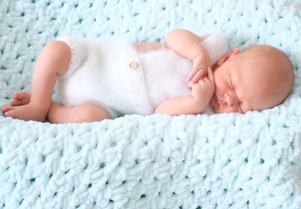 Un niño o niña recién nacido dormido yace sobre una manta de lana azul.Retrato de cerca de un niño — Foto de Stock