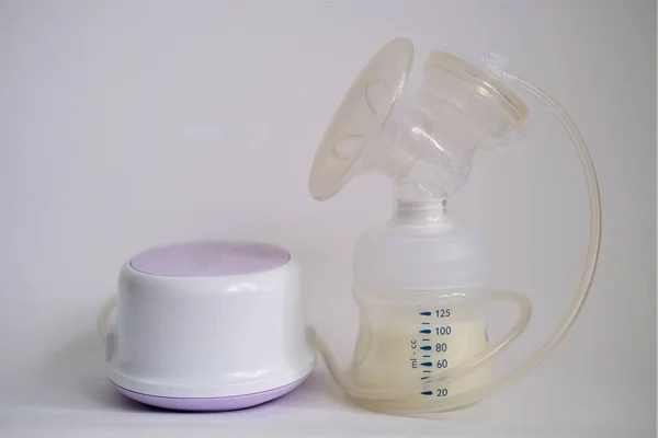 The electric breast pump is on the table in the kitchen. Give expressed breast milk. Breast care for a young mother