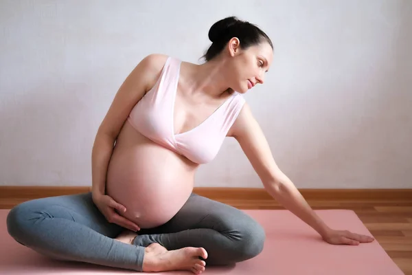 Een zwangere vrouw is bezig met yoga. Concept voedsel, gezonde levensstijl, sport. — Stockfoto