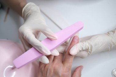 Profesyonel manikür, güzellik salonunda manikür. Eldivenler konusunda ustanın elleri. Tırnaklar parlatılıyor